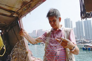 漁民羅金樹展示現代常用的漁網，與當年一樣套上鉛垂。（鍾卓恆攝）