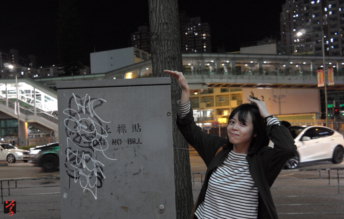 香港電箱觀察的運營者Jodie與荃灣路邊一個電箱的合影；電箱上有本地街頭藝術家k2production的標志性兔子圖案