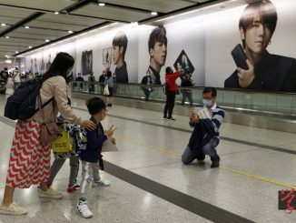 在平日上班族急速來往的香港站電梯通道裡，Mirror代言的大型廣告板成了假日一家大小、朋友的「打卡」熱點。（吳綽詩攝）