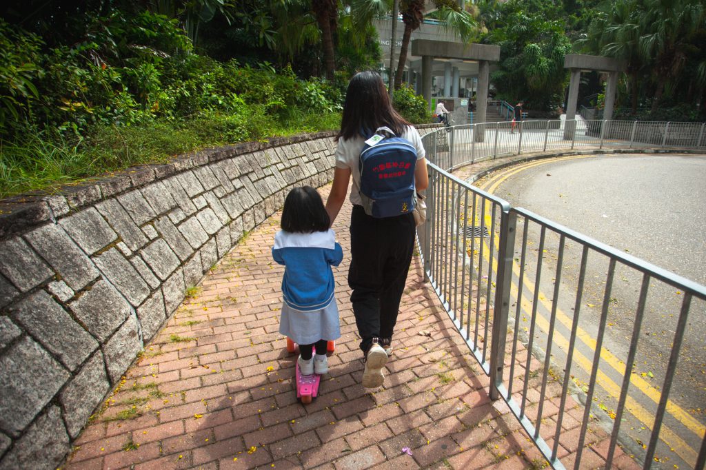 單親媽媽接女兒到學校旁的公園遊玩，女兒踩咗粉紅滑板車。