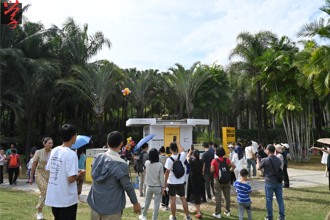 蓮花山公園美團空投櫃前，大量市民駐足拍照、體驗。「大學線」無人機穿梭城市中 外賣從天而降